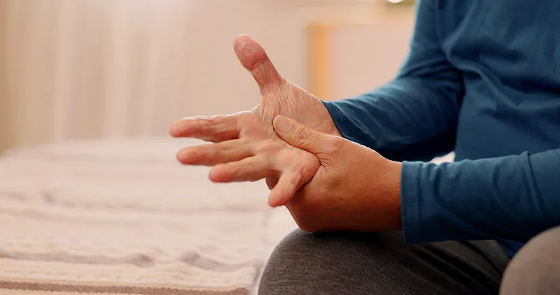 Mãos de pessoa idosa com tremor, apoiadas sobre o colo